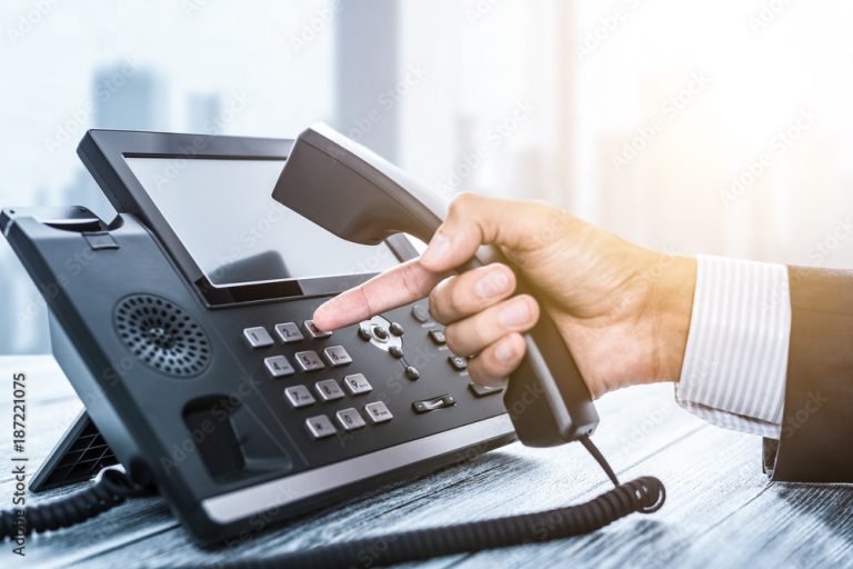 Hand wählt auf einem Bürotelefon